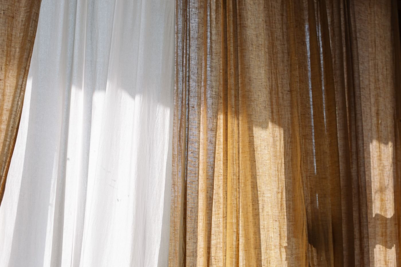 A white sheer beside a heavier linen curtain, both filling the frame